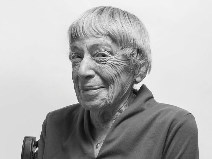 Elderly woman smiling warmly in a black and white portrait, representing common folk who made a mark in history.