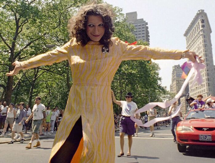 Person in yellow dress celebrating outdoors during a parade, showcasing common folk making a mark in history and society.