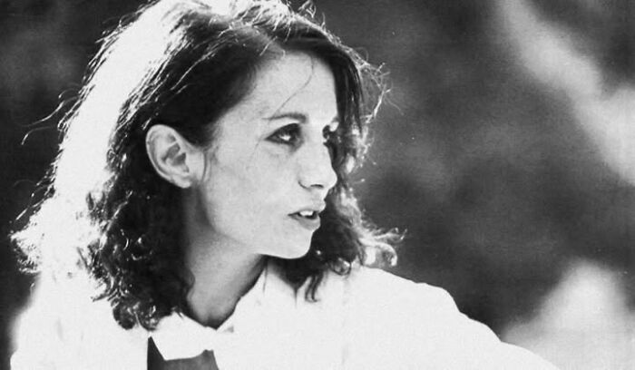 Black and white photo of a young woman with curly hair looking to the side, representing common folk making a mark in history.