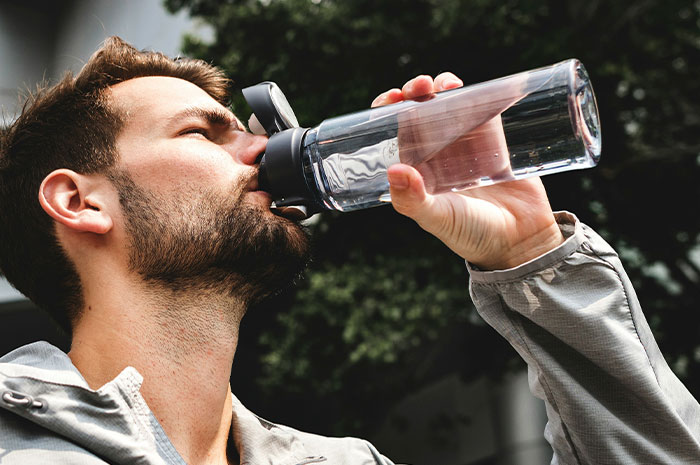 Man with beard drinking water from a bottle outdoors, reflecting on terrifying situation pilots have experienced in flight.