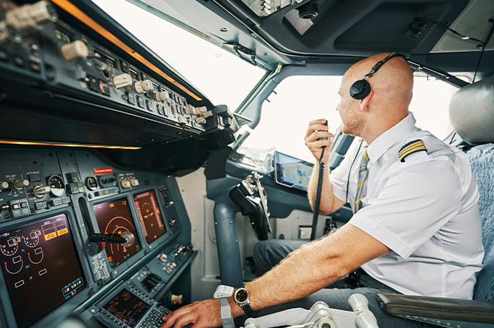 Pilot in cockpit using radio communication amid a tense situation in flight, focused on managing a terrifying scenario.