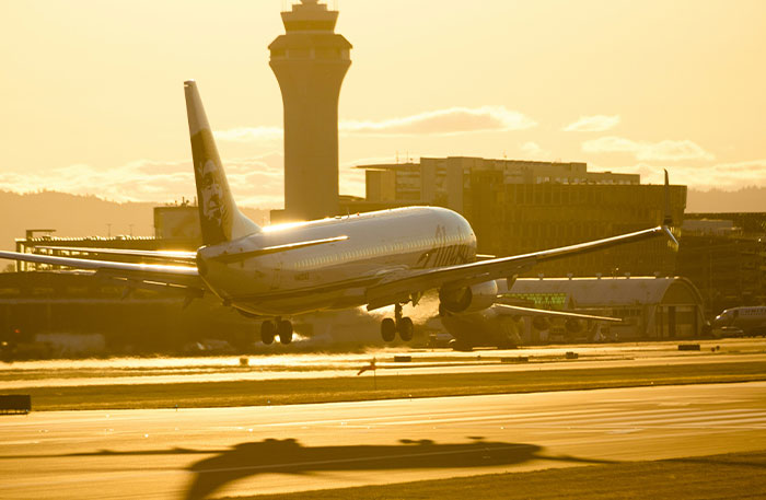Commercial airplane landing at sunset near airport control tower, illustrating pilots in terrifying situation during flight.