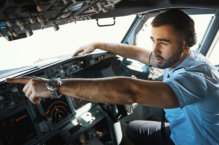Pilot wearing headset pointing at controls inside cockpit during a tense moment in a terrifying situation flight scenario