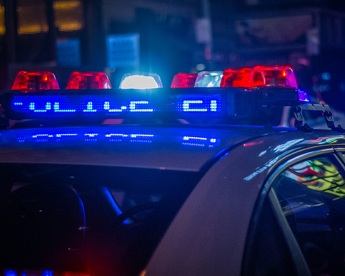 Police car with flashing red and blue lights at night, related to Batman villain homicide incident.
