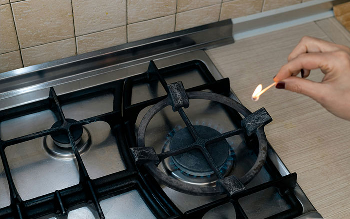 Hand lighting stove burner with match, illustrating wild situations cops had to deal with in memorable stories.