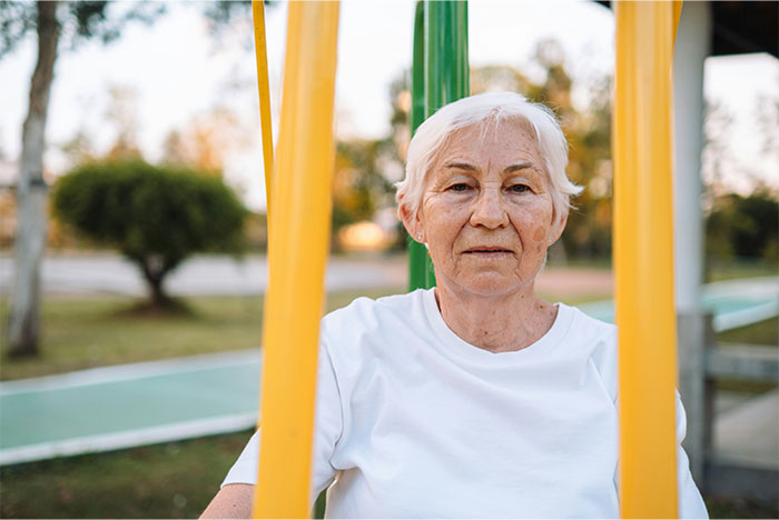 Elderly woman sitting at playground outdoors, conveying calm amid memorable wild situations cops had to deal with.
