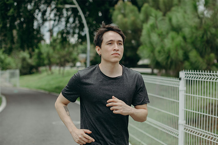 Young man running outside on a path near trees and fence, symbolizing memorable wild situations cops face.