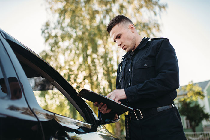 Police officer writing a ticket during a traffic stop, illustrating memorable wild situations cops deal with daily.