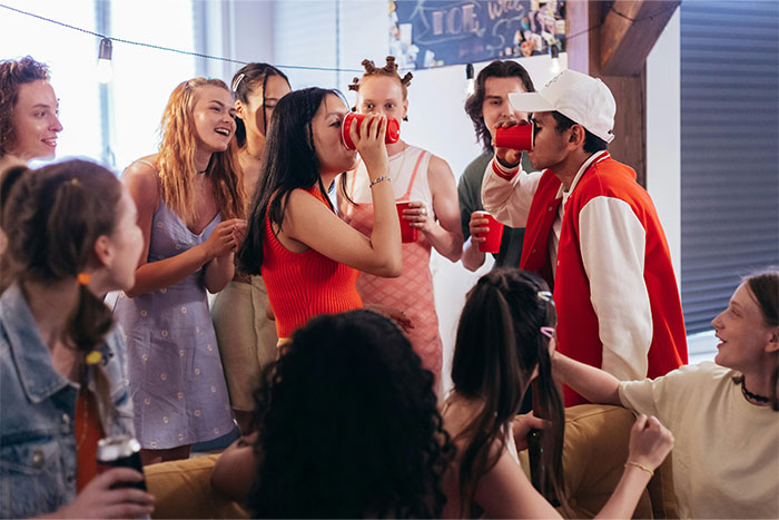 Group of young people drinking from red cups and laughing during a lively party capturing wild situations cops handle.