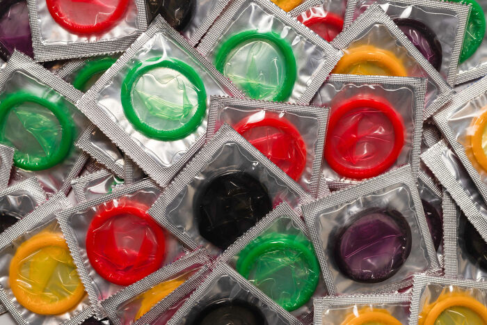 Colorful condoms in foil wrappers spread out, emphasizing police concerns over teenagers and illegal activities.