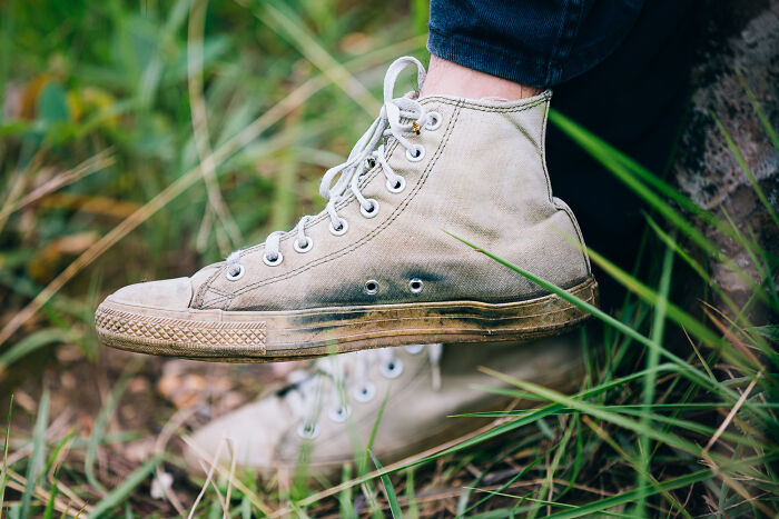 Close-up of a worn sneaker on teenager’s foot resting outdoors in grass, relating to police and illegal activities involving kids.