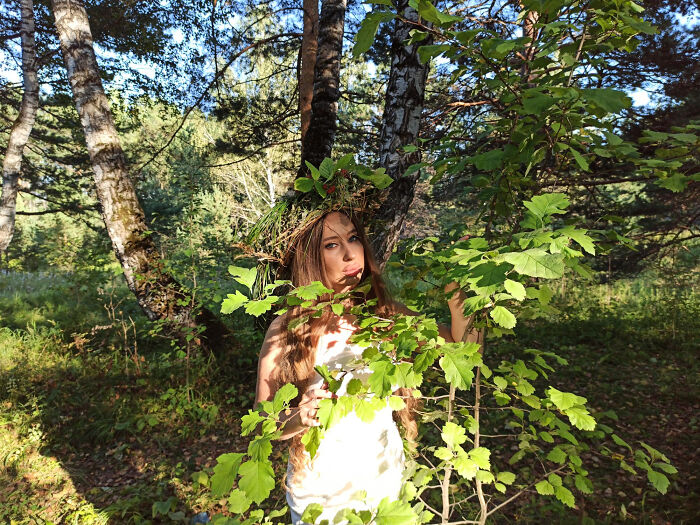 Teenager girl wearing a natural crown standing behind green leaves in a forest, evoking themes of police and illegal activities.