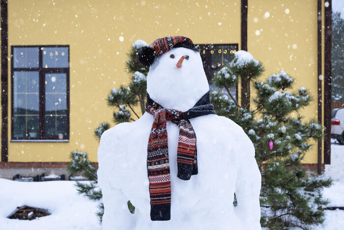 Snowman wearing a patterned scarf and hat outside a house during snowfall with police, teenagers, kids illegal theme.