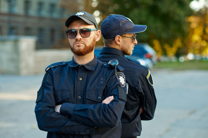 Two police officers standing back to back outdoors, focused on preventing illegal activities involving teenagers and kids.