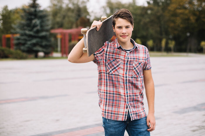 Teenager holding skateboard outdoors in a park, representing police concerns about teenagers and illegal activities.