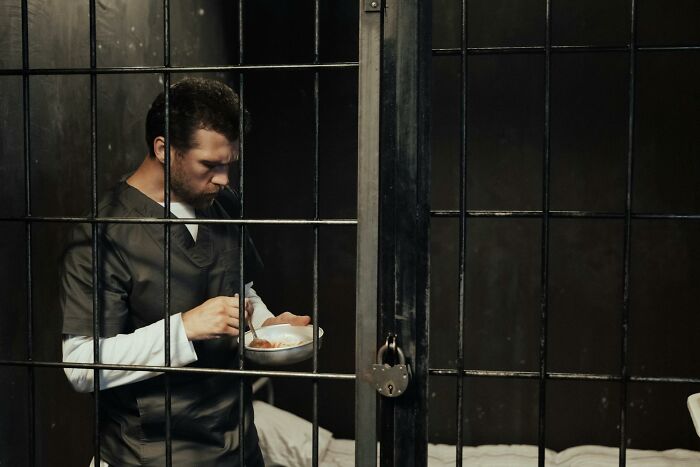 Teenager in prison cell eating from a bowl, illustrating police intervention with kids involved in illegal activities.