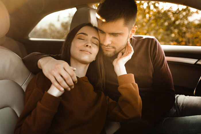 Teenagers sitting closely in a car with warm sunlight outside, depicting innocent moments before police involvement in illegal acts.