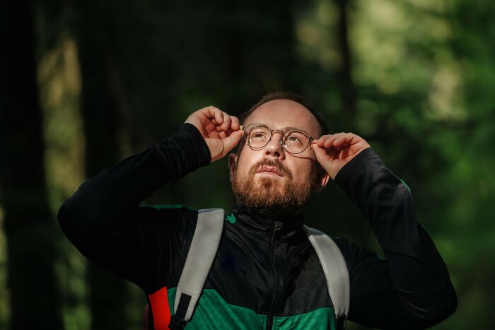 Man adjusting glasses while hiking in the woods, reflecting the sleepless fear after time spent in nature. - 21