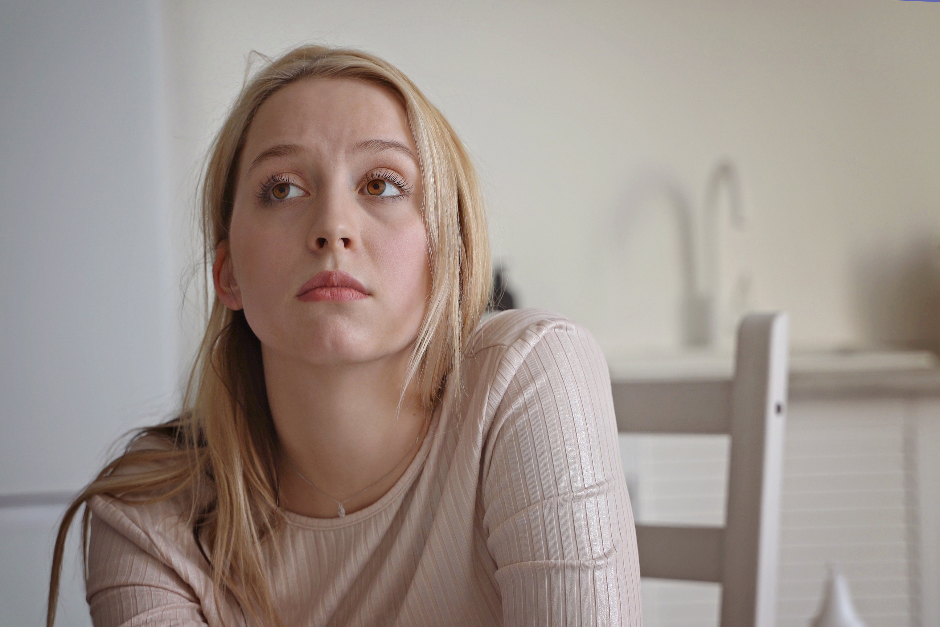 Young woman looking away thoughtfully at home, illustrating sister hijacks road trip and expects babysitting frustration. Young woman looking away thoughtfully at home, illustrating sister hijacks road trip and expects babysitting frustration.