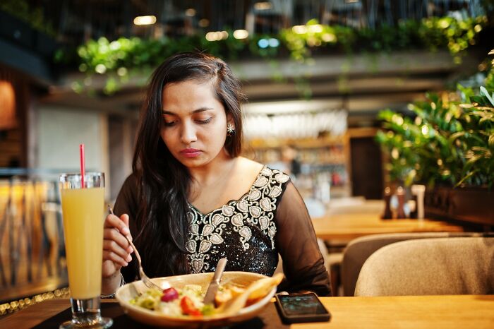 Restaurant worker maintaining a straight face while serving a unique and challenging food order in a busy dining setting.