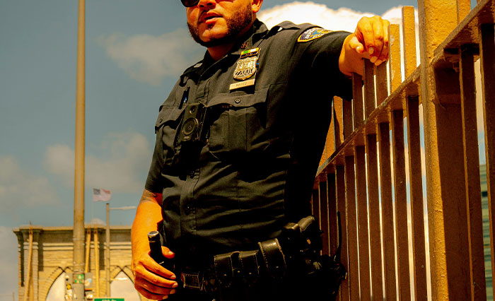 Prison officer in uniform standing outdoors by a fence, conveying experience related to Epstein death doubts.