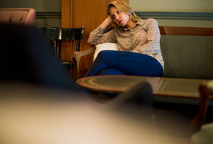 Woman sitting on couch looking puzzled during psychiatrist session in a cozy office setting with wooden furniture. Woman sitting on couch looking puzzled during psychiatrist session in a cozy office setting with wooden furniture.