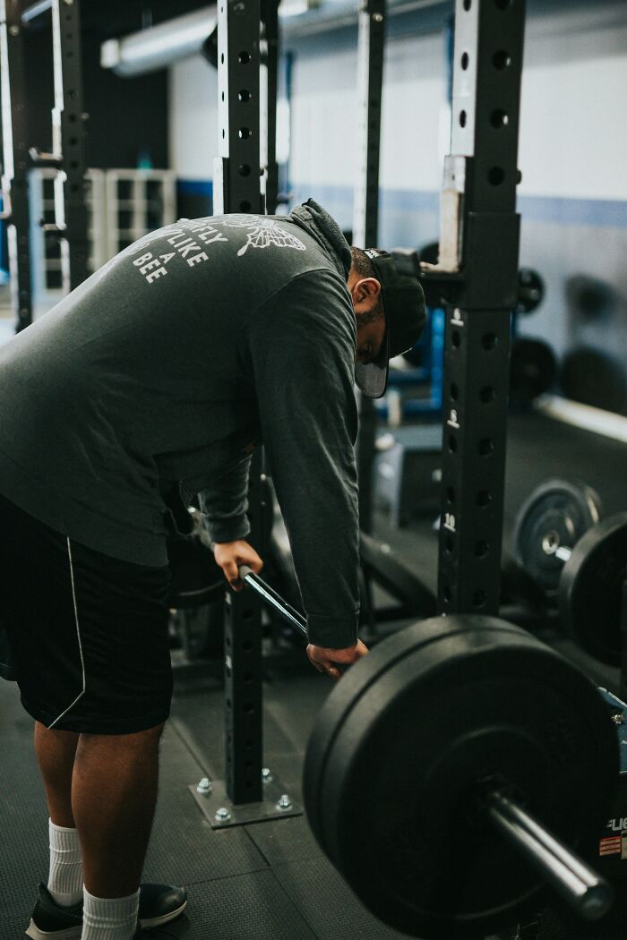 Man in gym preparing to lift weights, highlighting performative behaviors people can't stand in society.