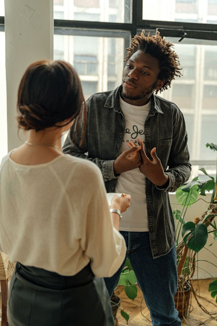 Two people having a serious conversation indoors illustrating performative behaviors in a social setting.