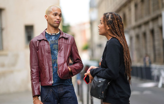 Two young adults having a casual conversation outdoors, illustrating mood-based questions to ask your crush.