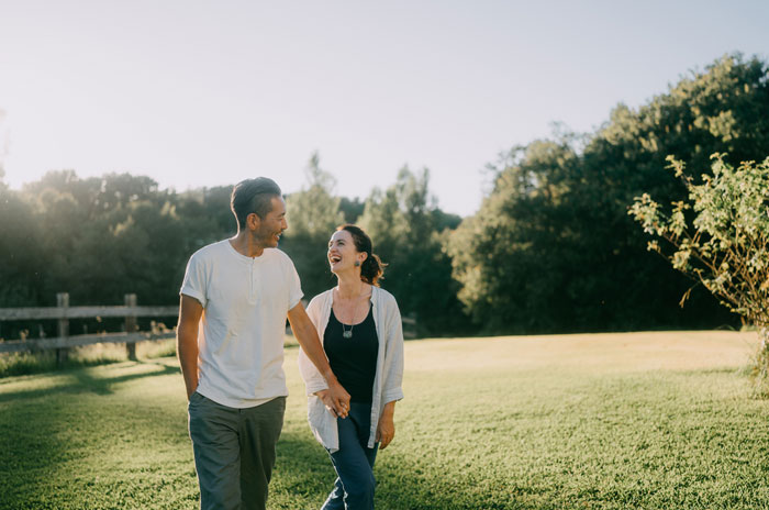 Couple holding hands and smiling outdoors, capturing mood-based questions to ask your crush in a natural setting.