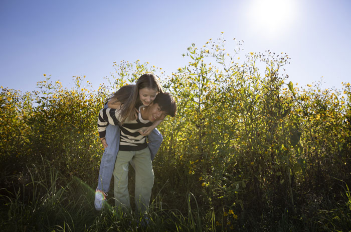 Young couple outdoors with boy giving girl a piggyback, enjoying a playful moment for mood-based questions with crush.