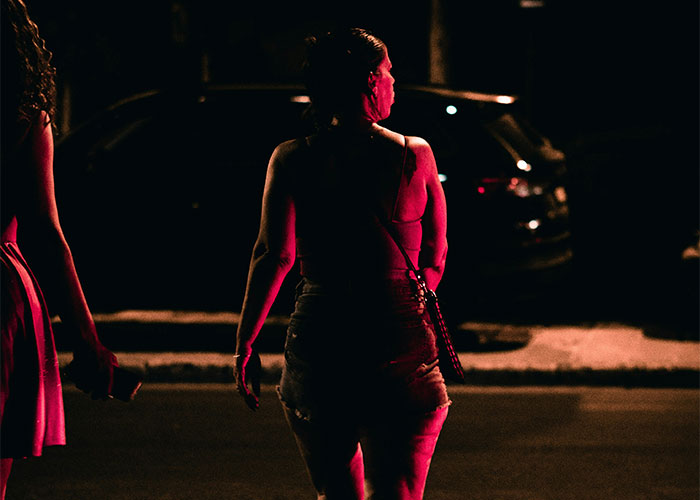 Two women walking at night lit by red streetlights, illustrating quick reactions preventing a tragedy scenario.