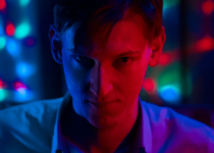 Man with half-lit face in red and blue lighting, illustrating quick reactions preventing a tragedy in a dramatic scene.
