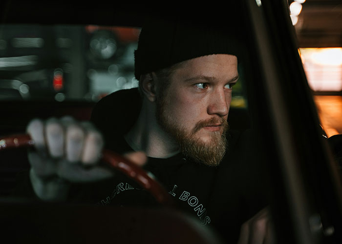 Man focused inside a car, showing quick reactions while driving to prevent a tragedy in a dimly lit environment.