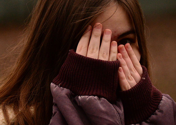 Young woman covering her face with hands, illustrating quick reactions preventing a tragedy in a natural outdoor setting.
