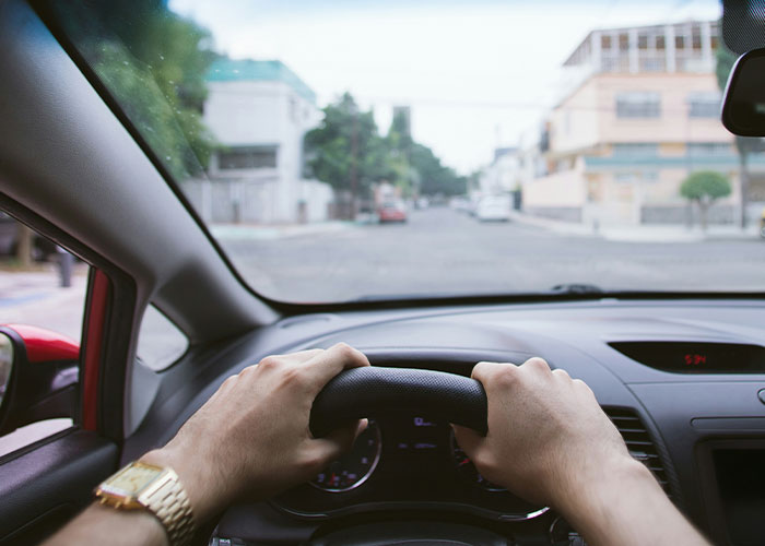 Driver with quick reactions gripping steering wheel, focused on preventing a tragedy while driving through a city street.
