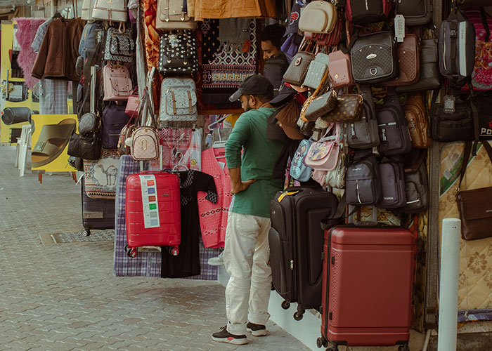 Man inspecting handbags and luggage at a street market, showcasing quick reactions preventing a tragedy in busy area.