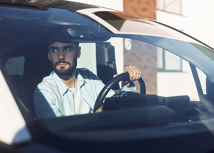 Man with a beard showing quick reactions while driving a car, preventing a potential tragedy on the road.