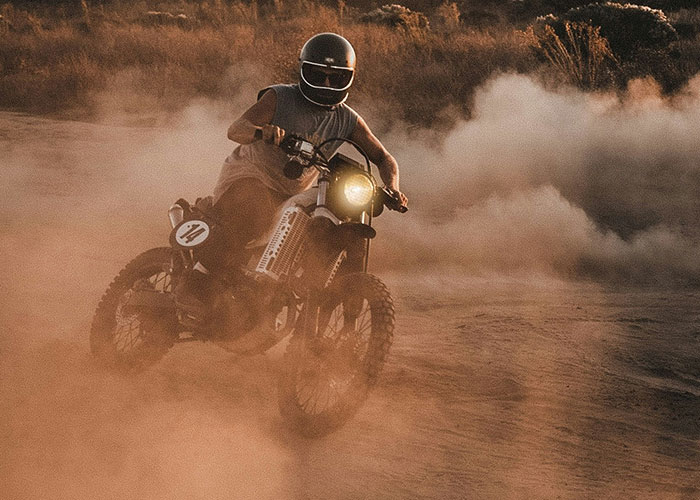 Motorcyclist with quick reactions riding through dusty terrain, preventing potential tragedy with skillful control.