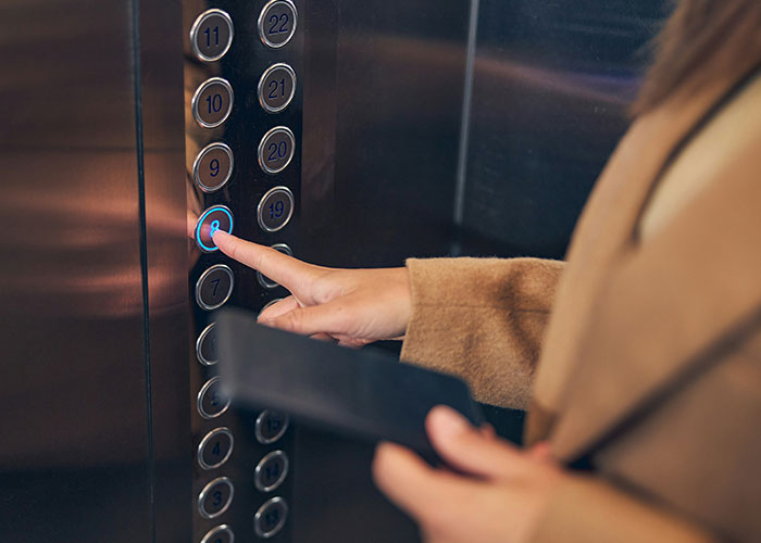Person pressing elevator button, illustrating quick reactions preventing a tragedy in an urgent moment.