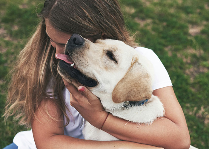Woman hugging a Labrador dog outdoors, illustrating quick reactions that prevent a tragedy through close connection and care.