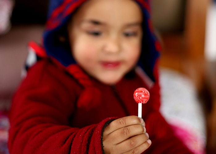 Child in a red hoodie holding a red and white lollipop, illustrating quick reactions preventing a tragedy scenario.
