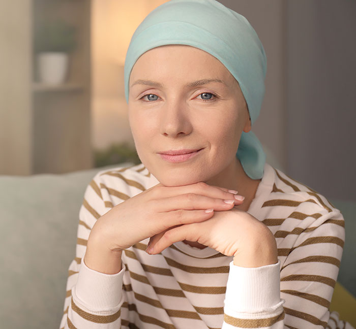 Woman wearing a headscarf sitting calmly indoors, reflecting a peaceful moment possibly after a therapeutic session.