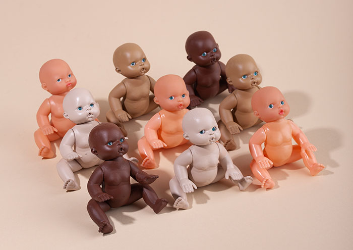 Diverse plastic dolls sitting together against a beige background, symbolizing rage room customers who need therapy.