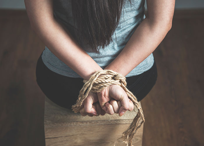 Person with hands tied behind back with rope, depicting real-life terror and paranoia scenarios.