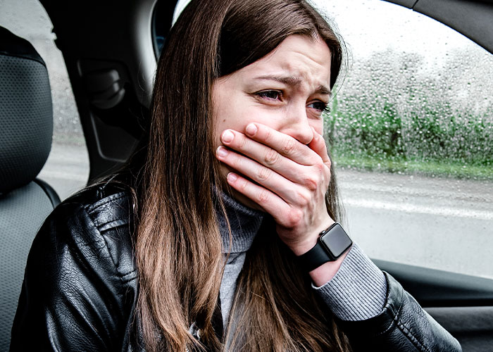 Woman inside a car looking terrified and covering her mouth, capturing a moment of real-life terror and paranoia.