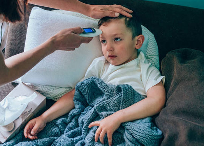 Sick child wrapped in blanket having temperature checked by adult, illustrating real-life terror moments and paranoia fears.