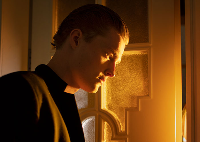 Young man caught in a tense moment, illustrating paranoia and real-life terror in a dimly lit setting.