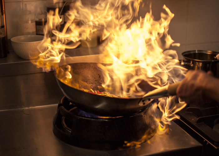 Wok flaming with intense fire on stove, illustrating real-life terror moments people face beyond paranoia.