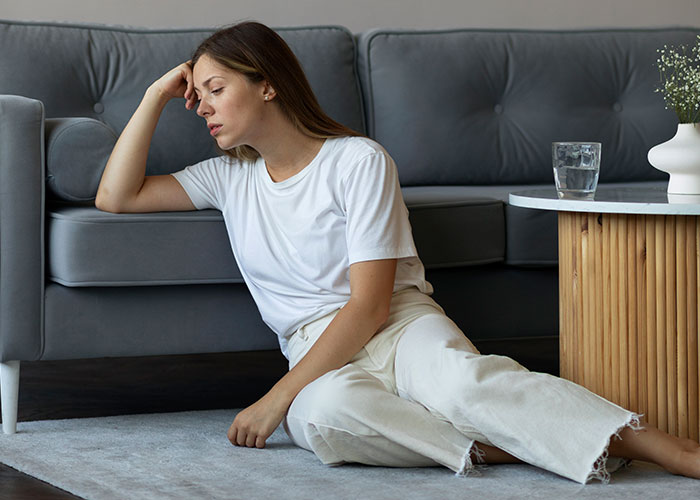 Young woman sitting on the floor in distress, appearing paranoid and facing real-life terror in a home setting.